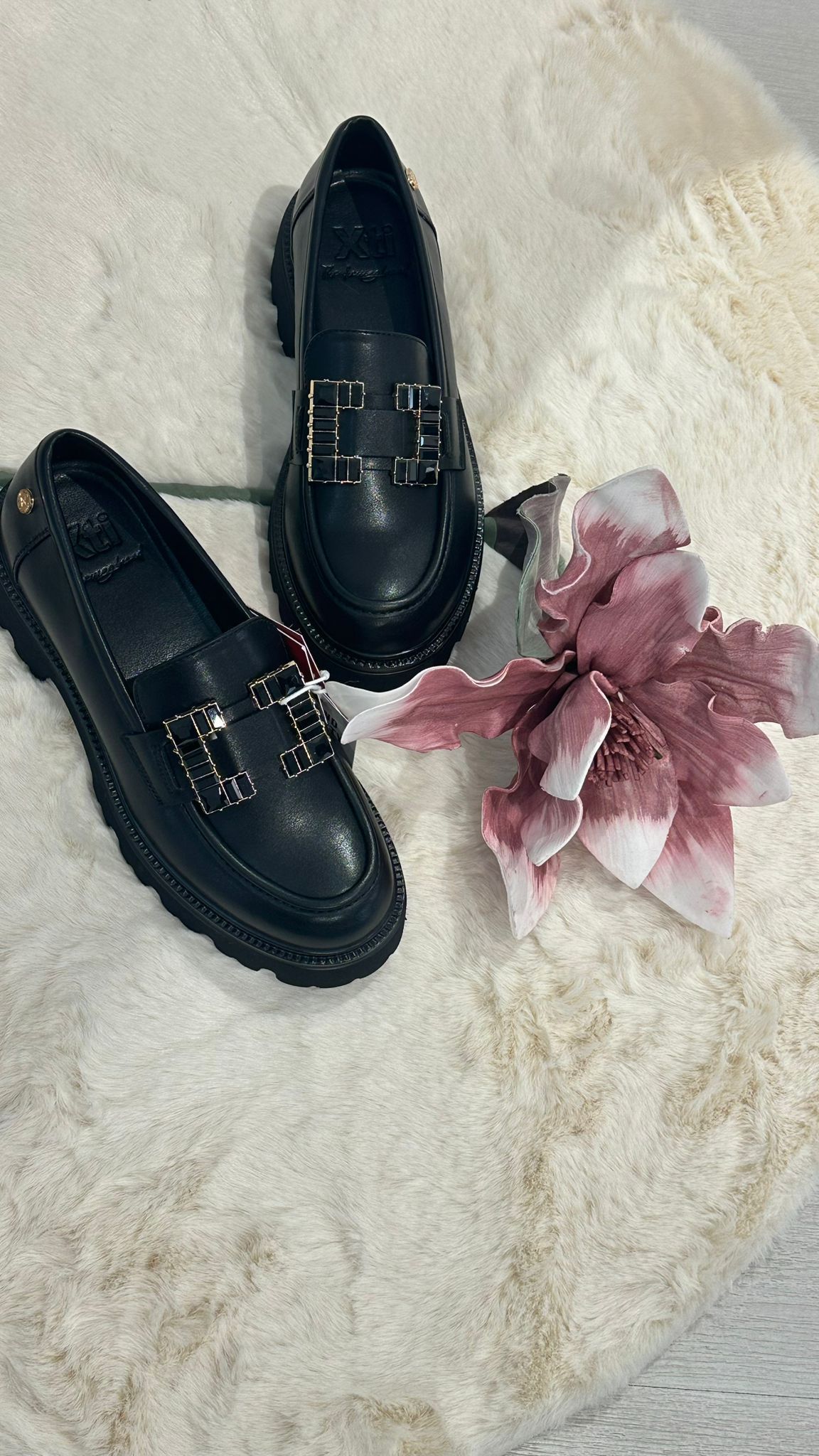 Scarpe sugli scaffali esposti in un negozio, di vari colori, con una parete bianca sullo sfondo.