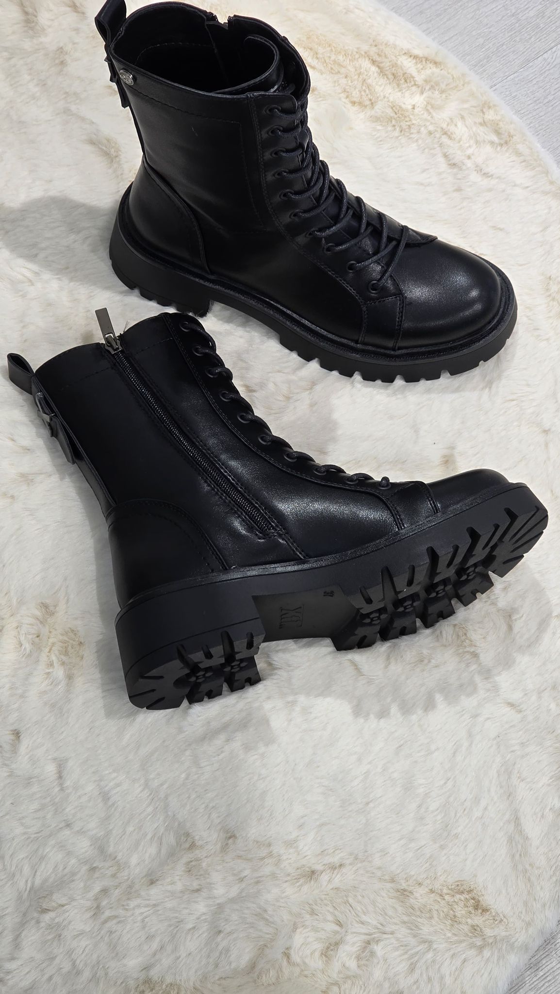 Le scarpine bianche con i fiocchi sono appoggiate su una superficie colorata a strisce arcobaleno.