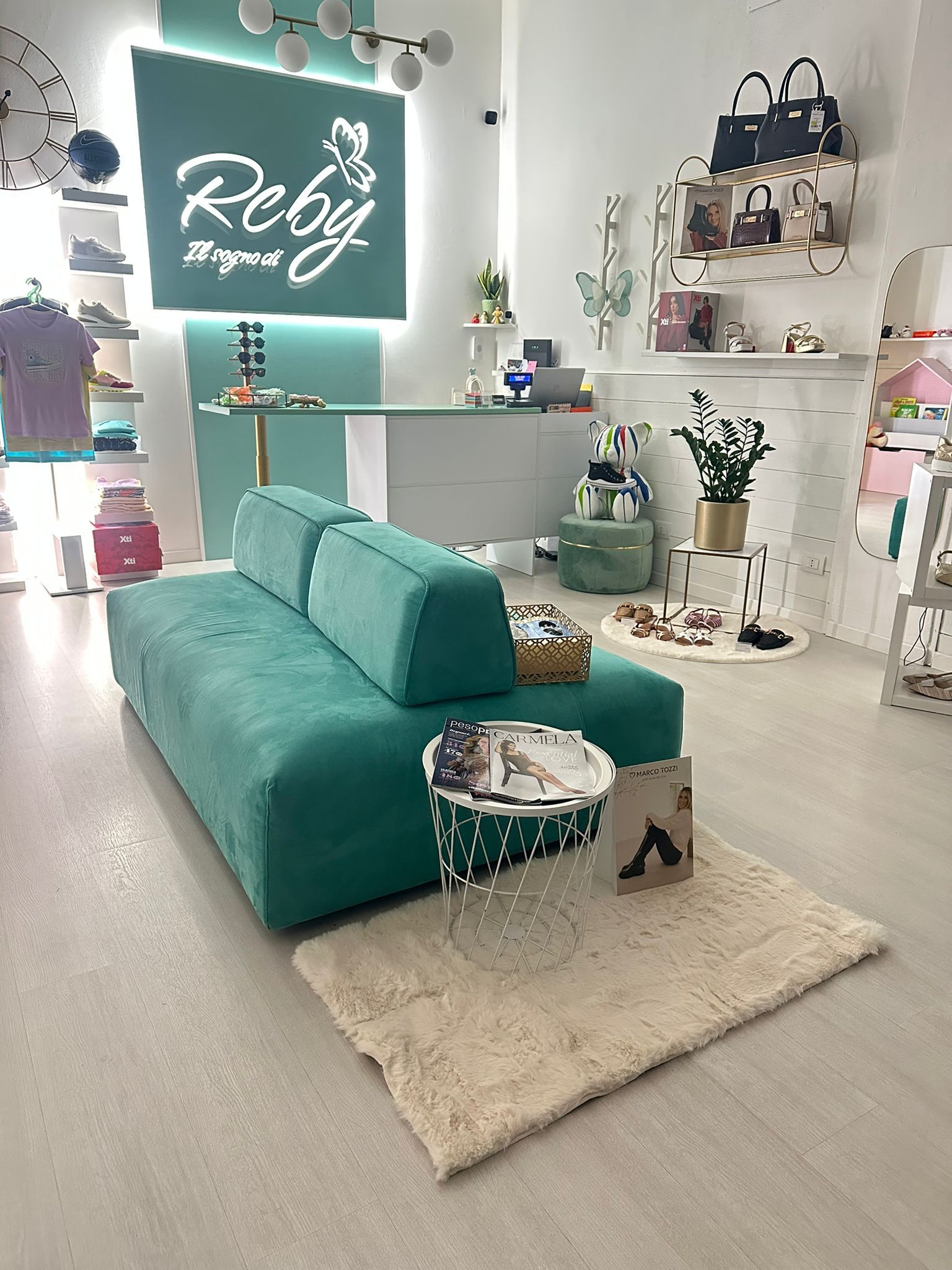 Un divano color verde acqua in una boutique con decorazioni turchesi e bianche. Insegna del negozio Reby.