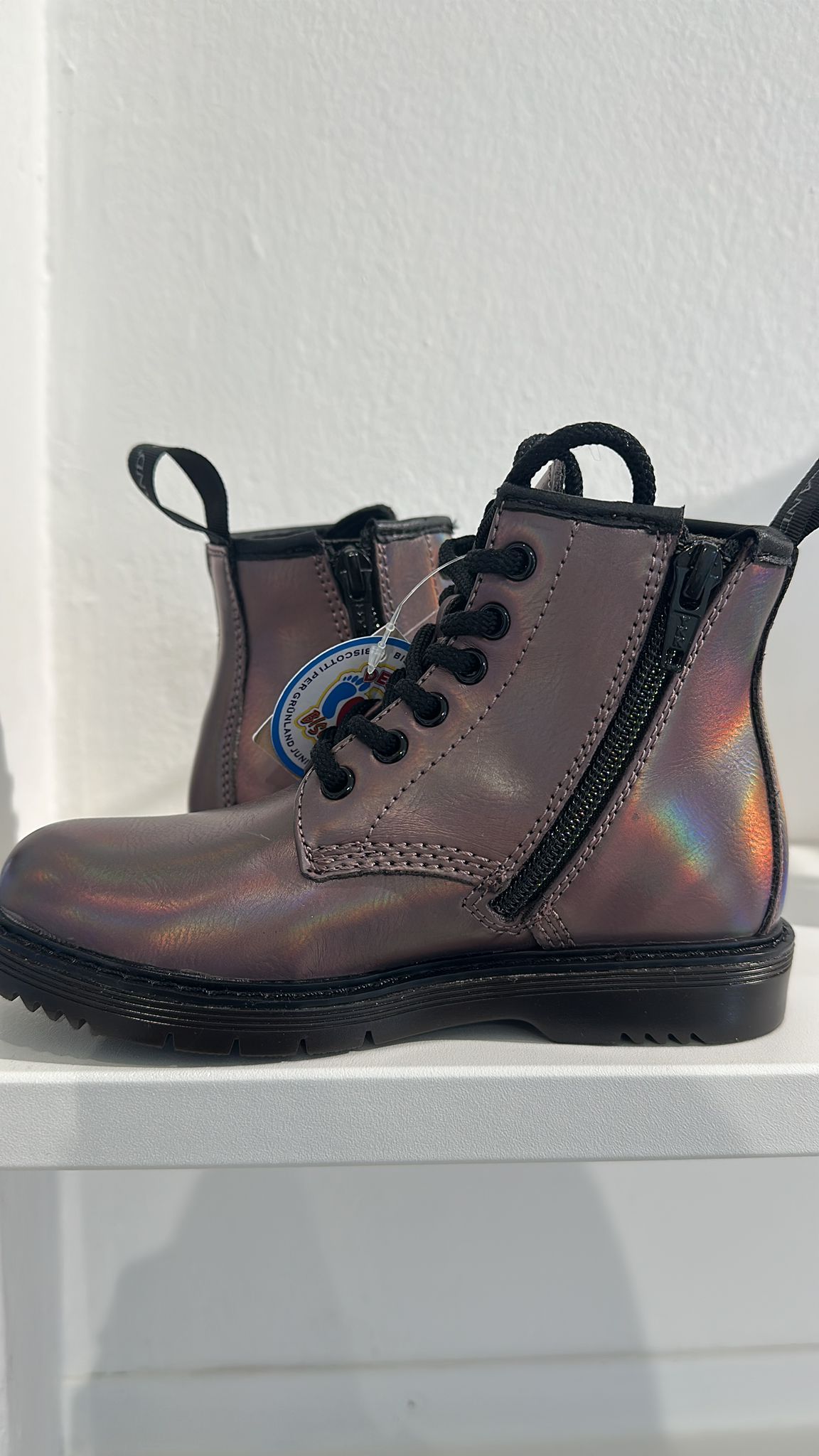 Stivaletti viola lucidi con lacci neri e cerniera, su uno scaffale.