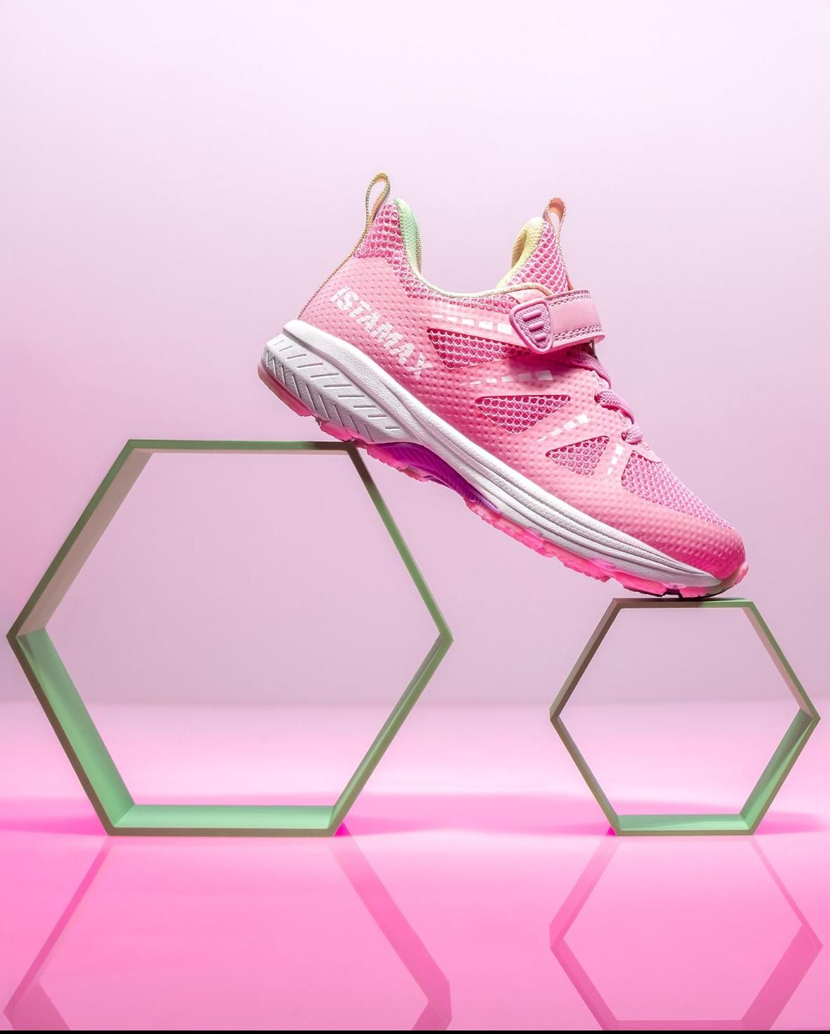 Scarpa sportiva rosa su zeppe esagonali verdi, su sfondo rosa.