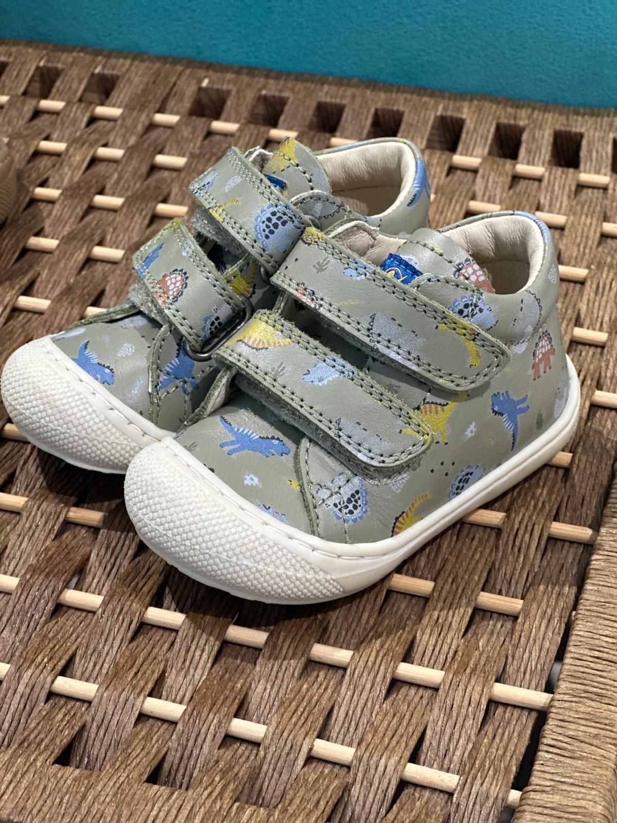 Scarpe per bambini grigie con stampa blu e gialla, due cinturini in velcro, suole bianche.