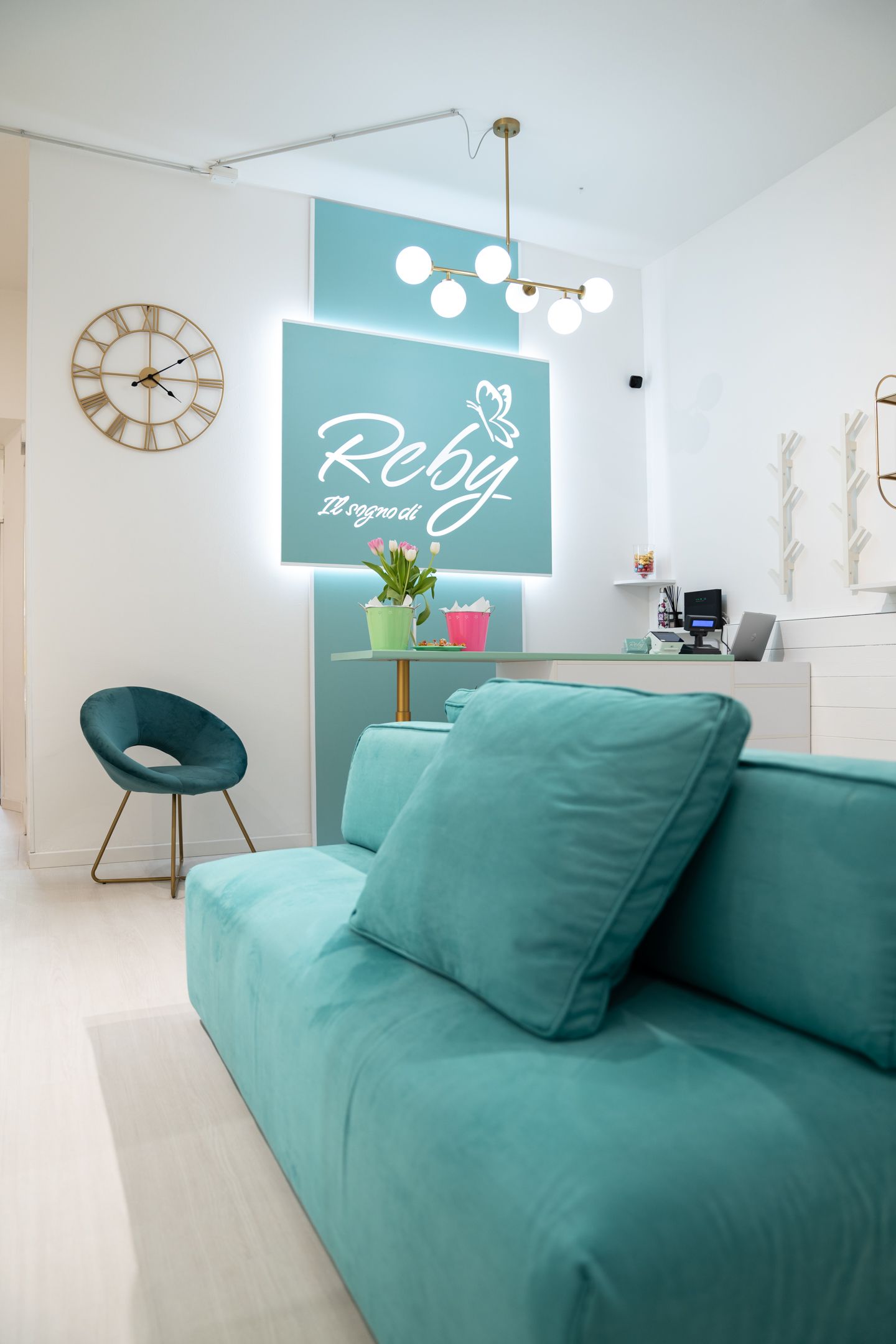 Divano e poltrona color verde acqua in una stanza moderna con un'insegna al neon con la scritta 