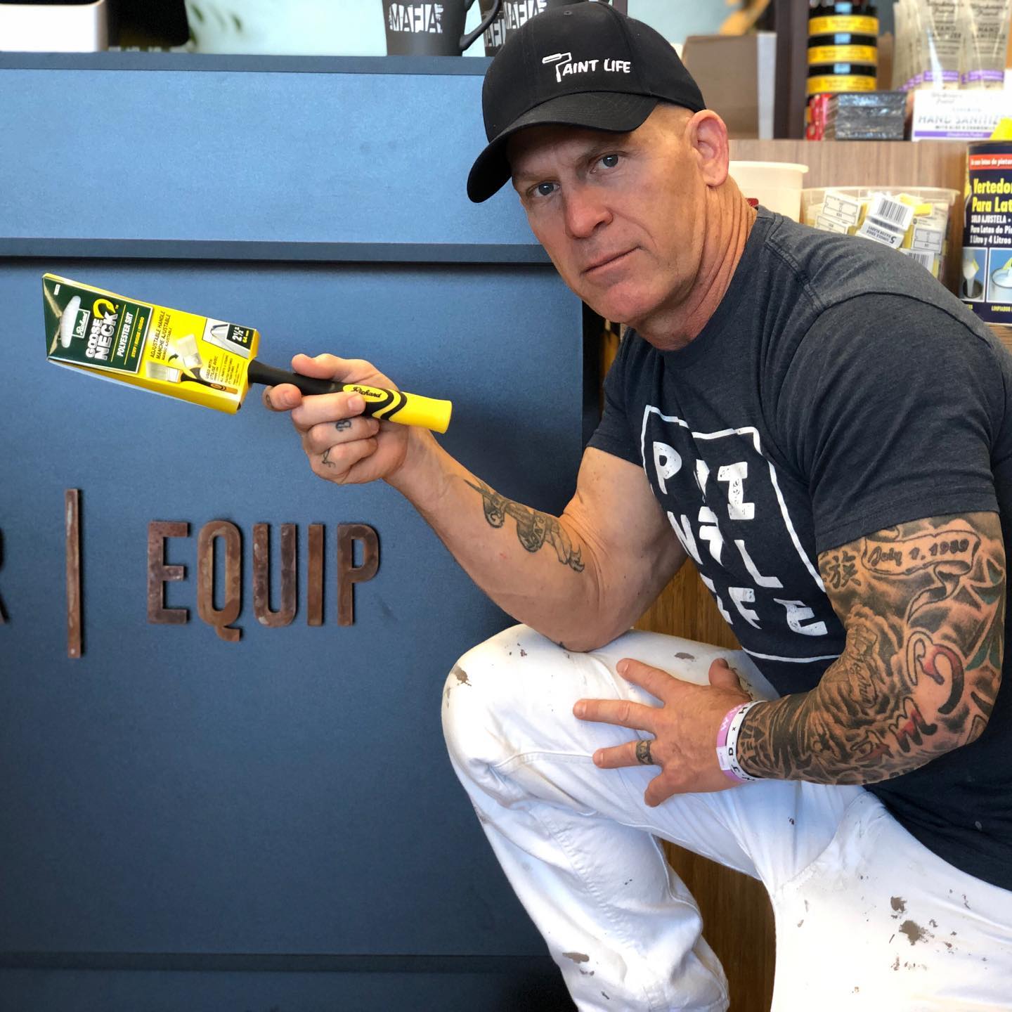 The Idaho Painter holding a Gooseneck brush in front of a sign that says equip