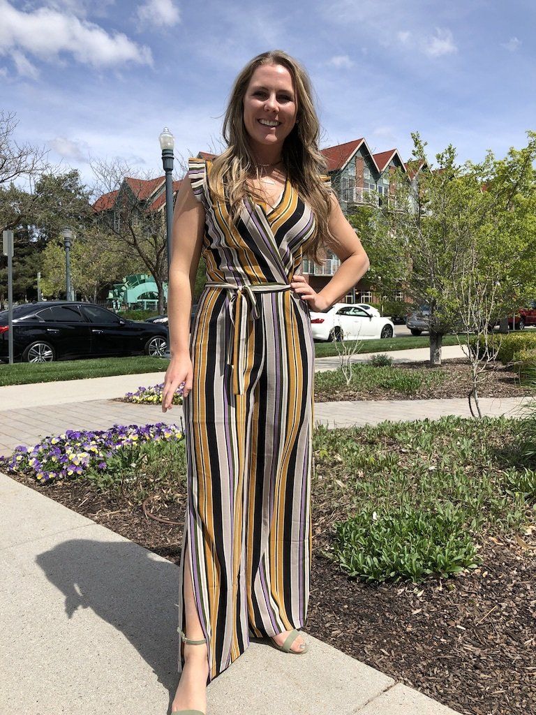 A woman in a striped jumpsuit is standing on a sidewalk.