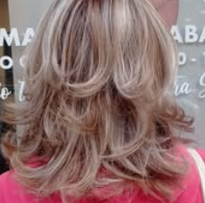 Una donna con lunghi capelli biondi è in piedi davanti a una finestra.