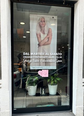 Una donna è in piedi davanti a una finestra su cui è appeso un cartello.