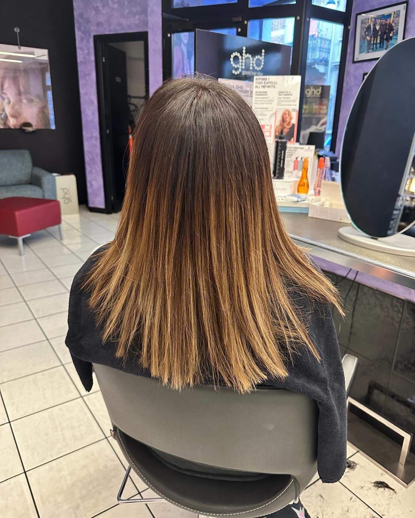 Una donna è seduta su una sedia in un salone da parrucchiere.