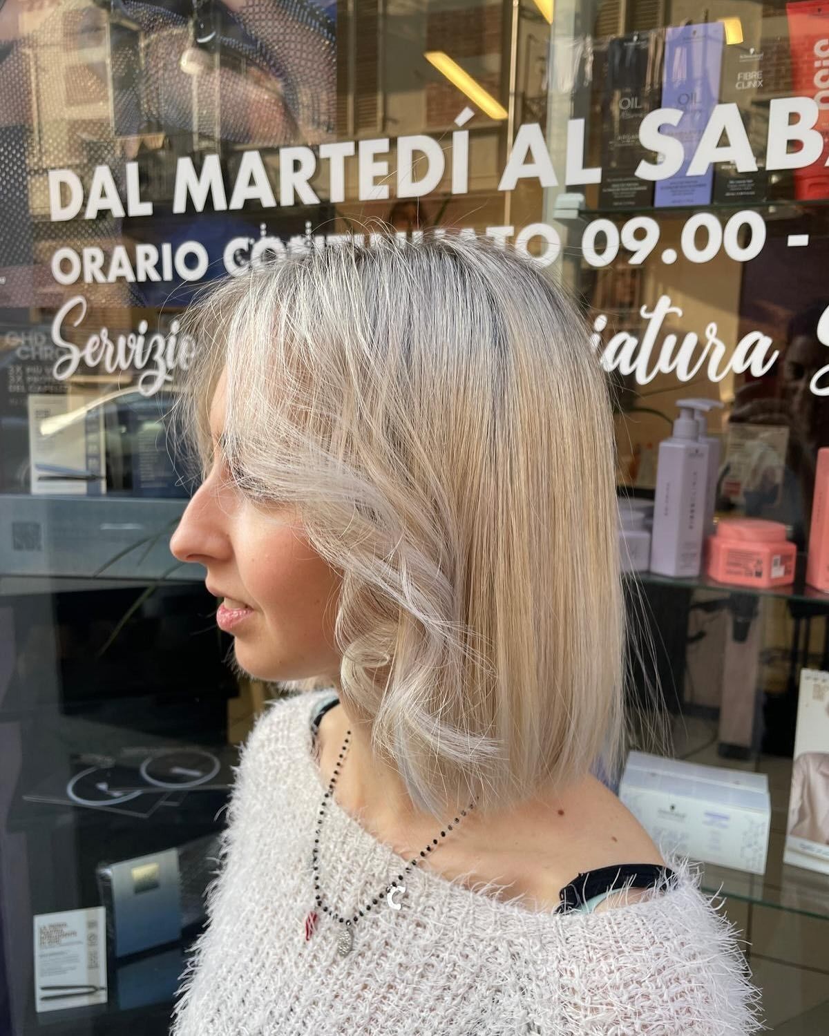 Una donna è in piedi davanti a una finestra su cui è scritto dal martedi al sab