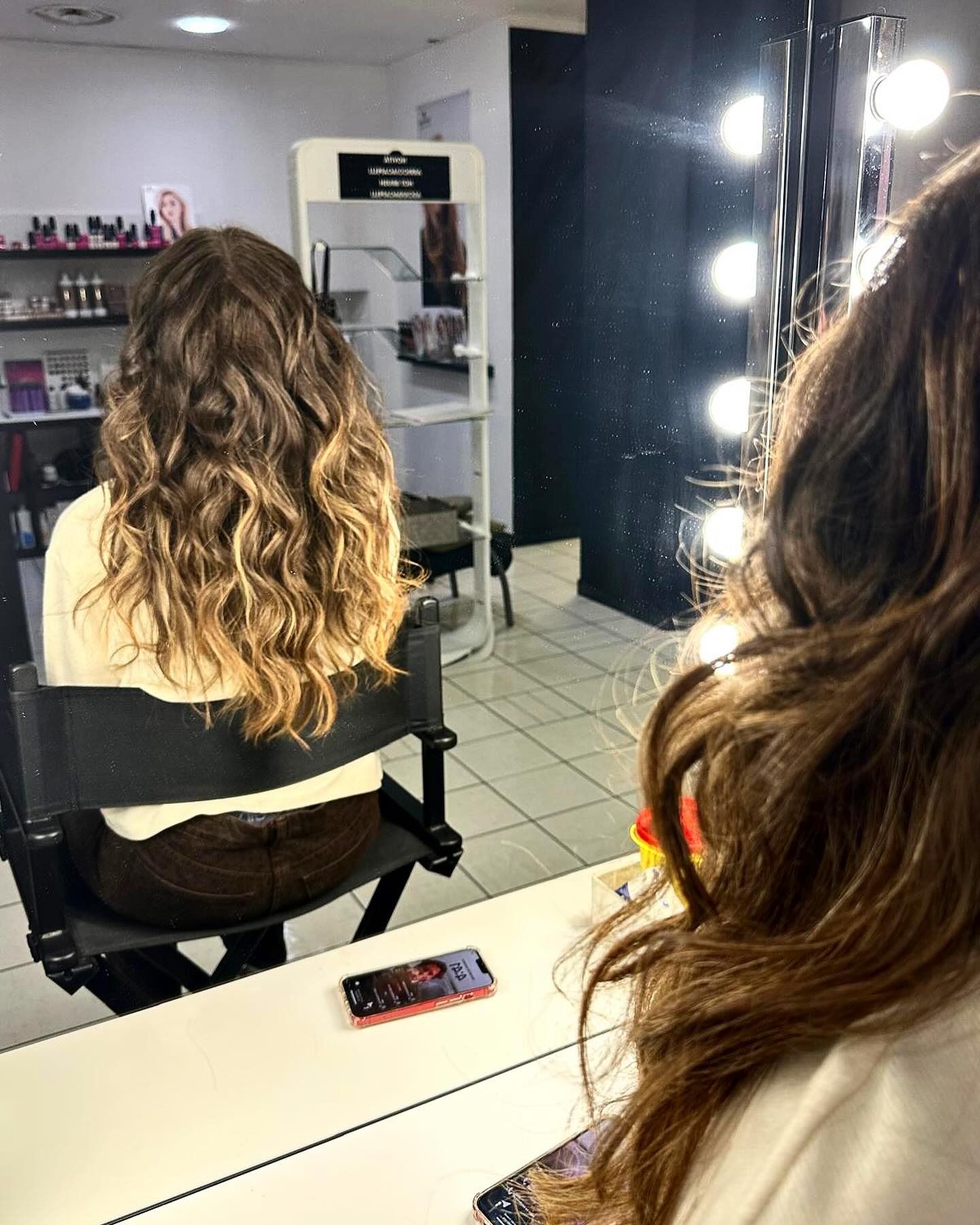 Una donna è seduta su una sedia davanti a uno specchio in un salone.