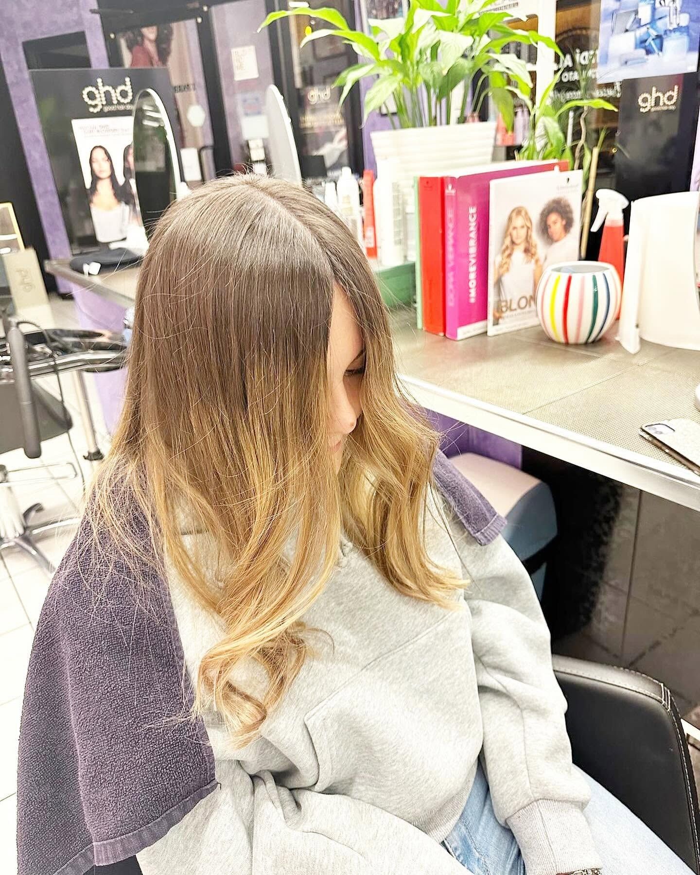 Una donna è seduta su una sedia in un salone con i capelli avvolti in un asciugamano.