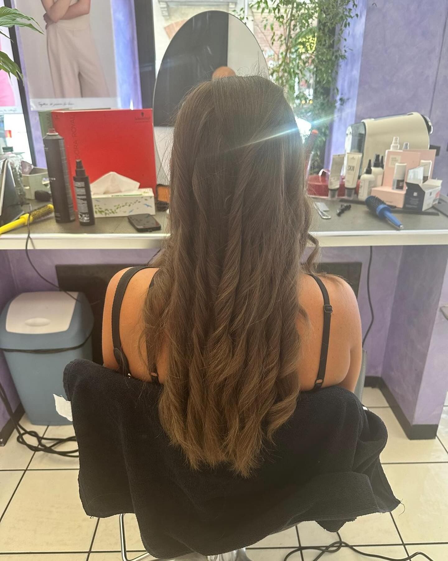 Una donna con i capelli lunghi è seduta su una sedia in un salone.