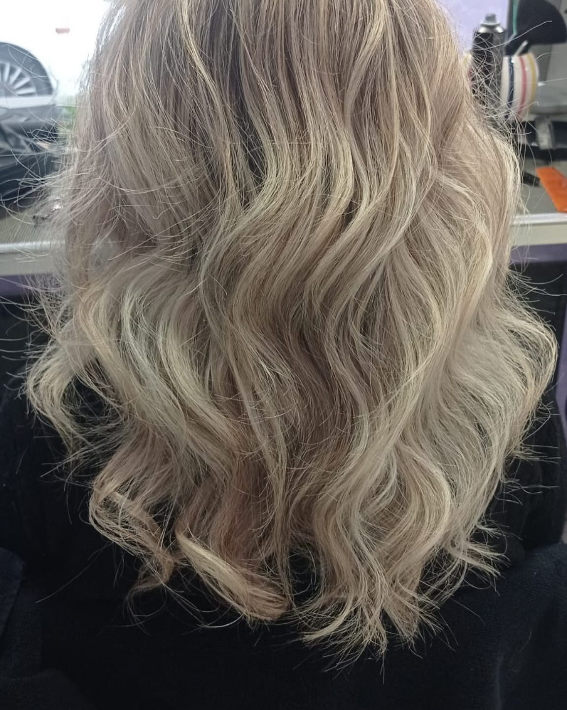 Un primo piano dei capelli biondi di una donna in un salone.