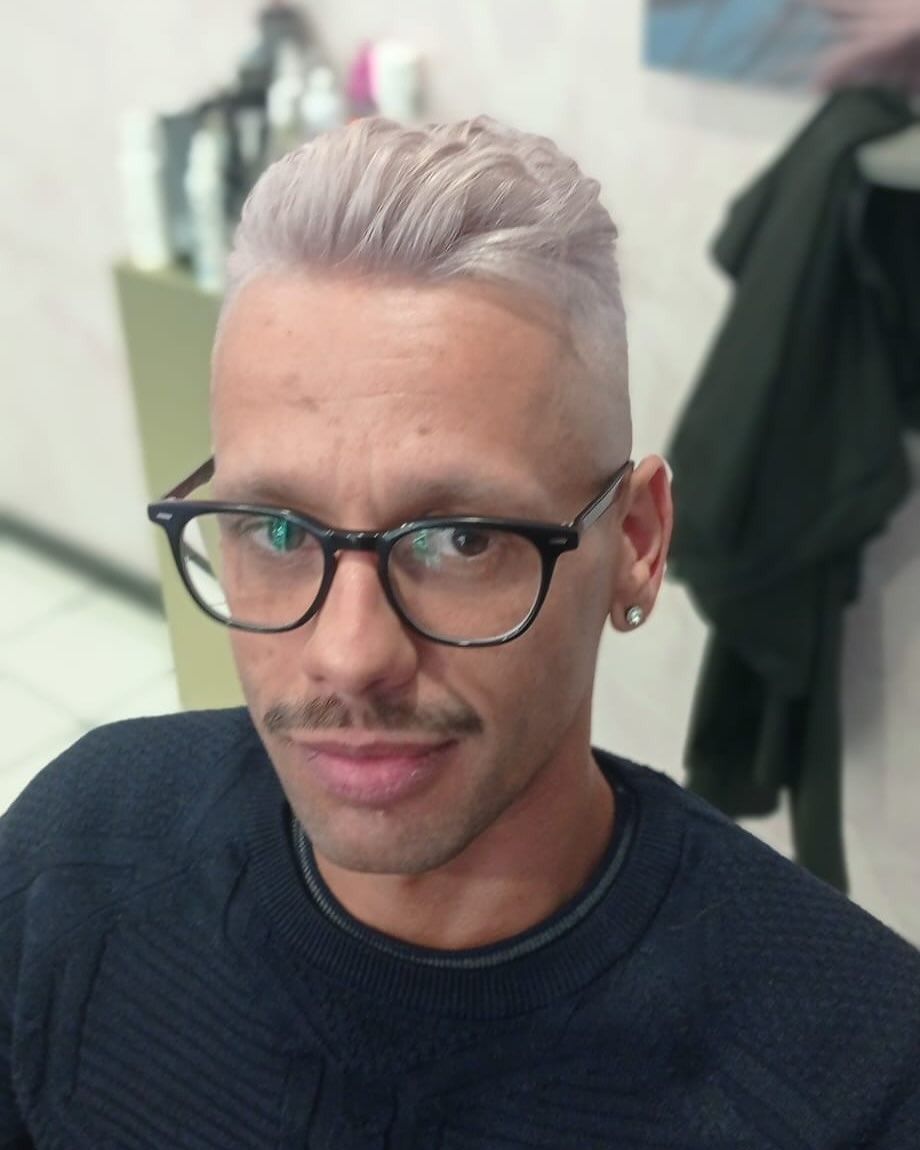 Un uomo con occhiali e baffi indossa una camicia nera