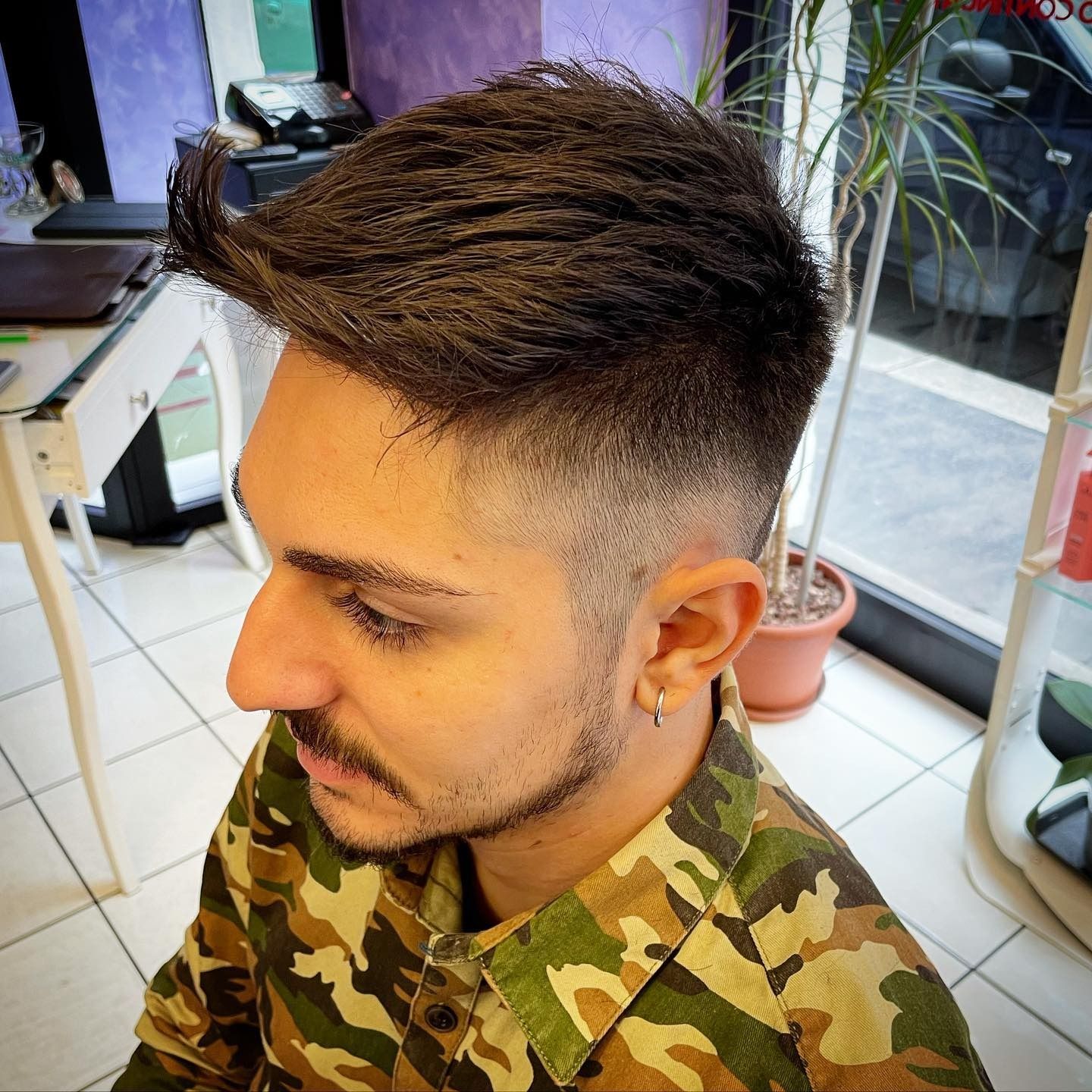 Un uomo con la barba che indossa una camicia mimetica