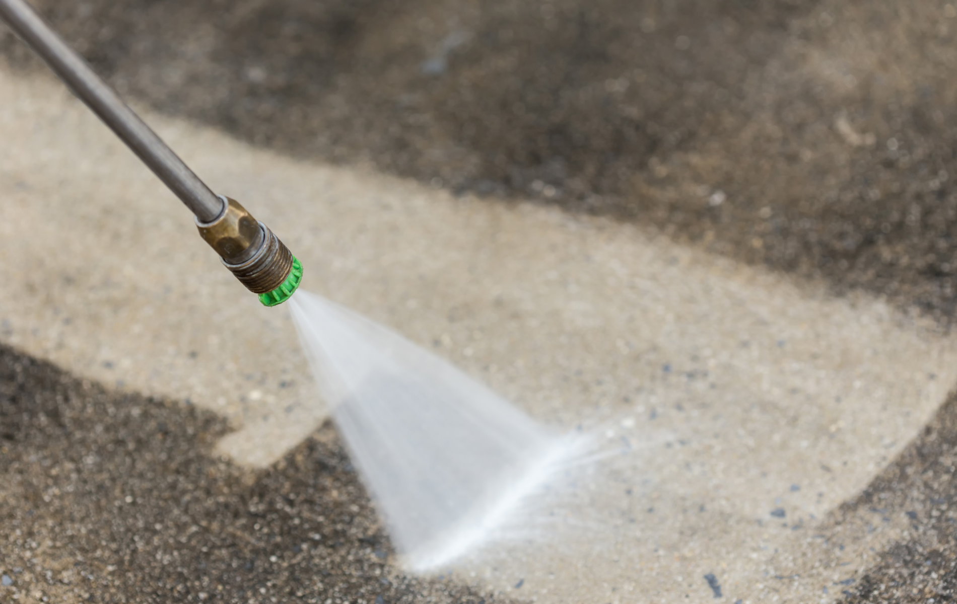 A person is using a high pressure washer to clean a concrete floor.