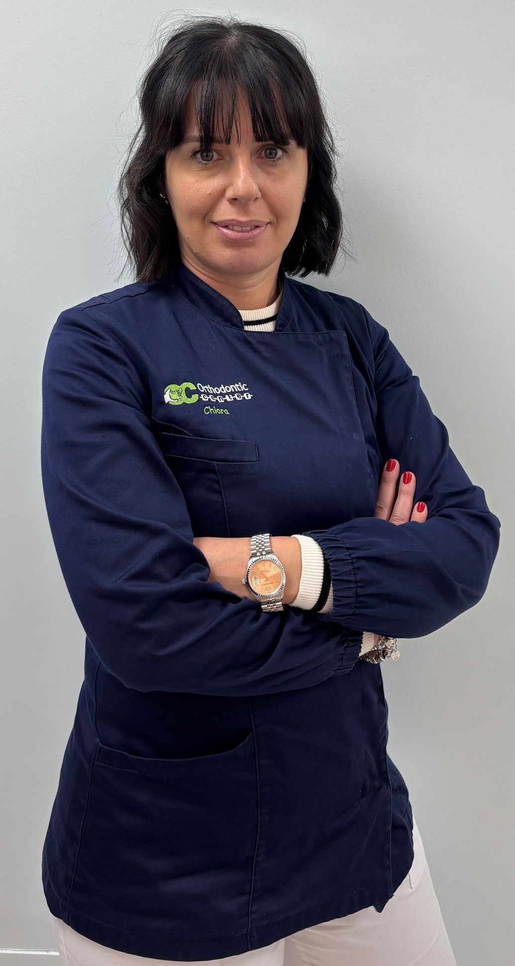 Una donna con una giacca blu è in piedi con le braccia incrociate.