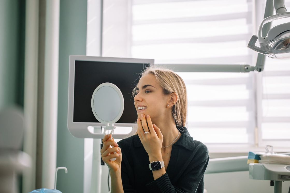 Una donna si guarda i denti allo specchio in uno studio dentistico.