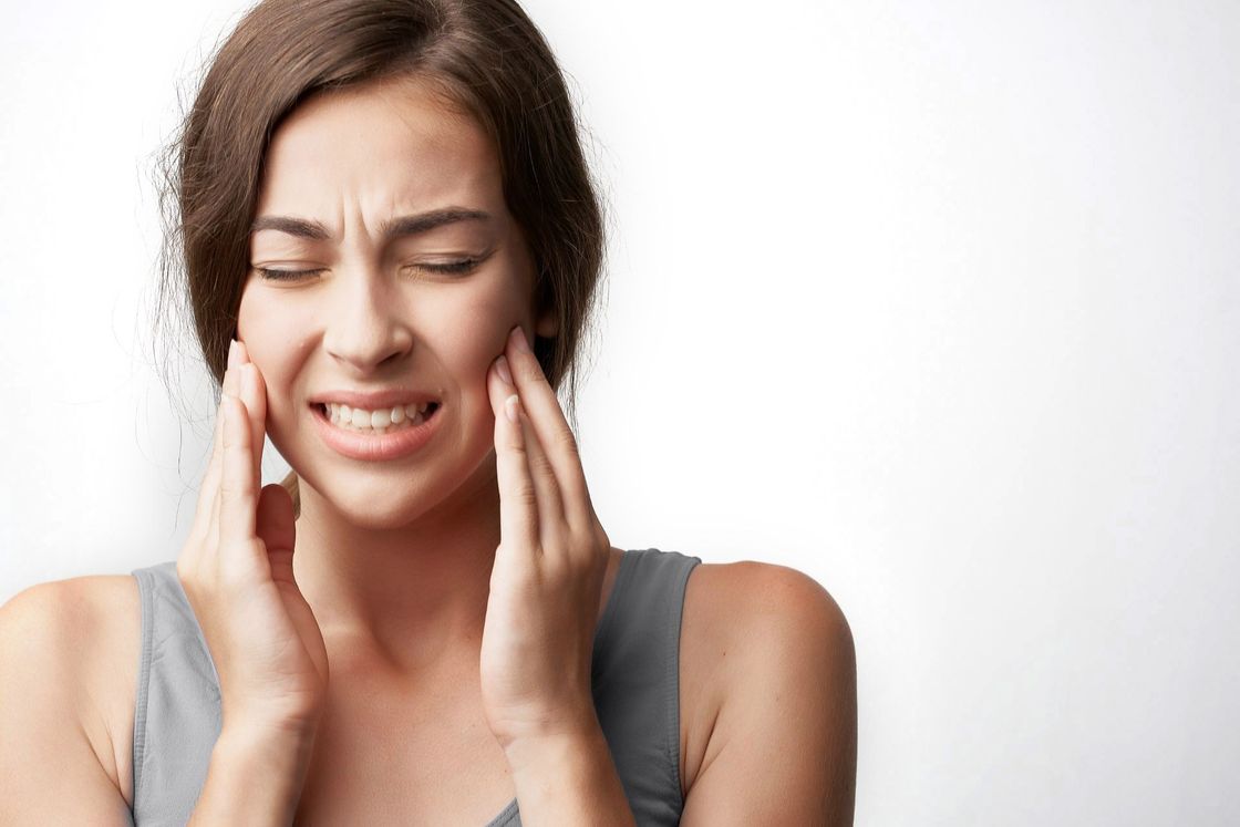 Una donna si tiene il viso dolorante a causa del mal di denti.