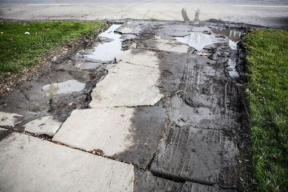 Driveway concrete full of cracks, potholes, and uneven surfaces