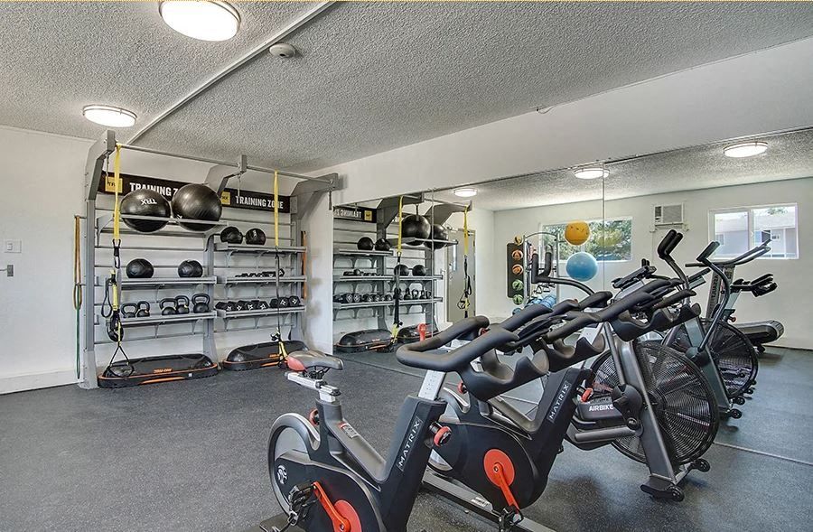 Indoor property gym with stationary bikes, weight racks, and fitness equipment.