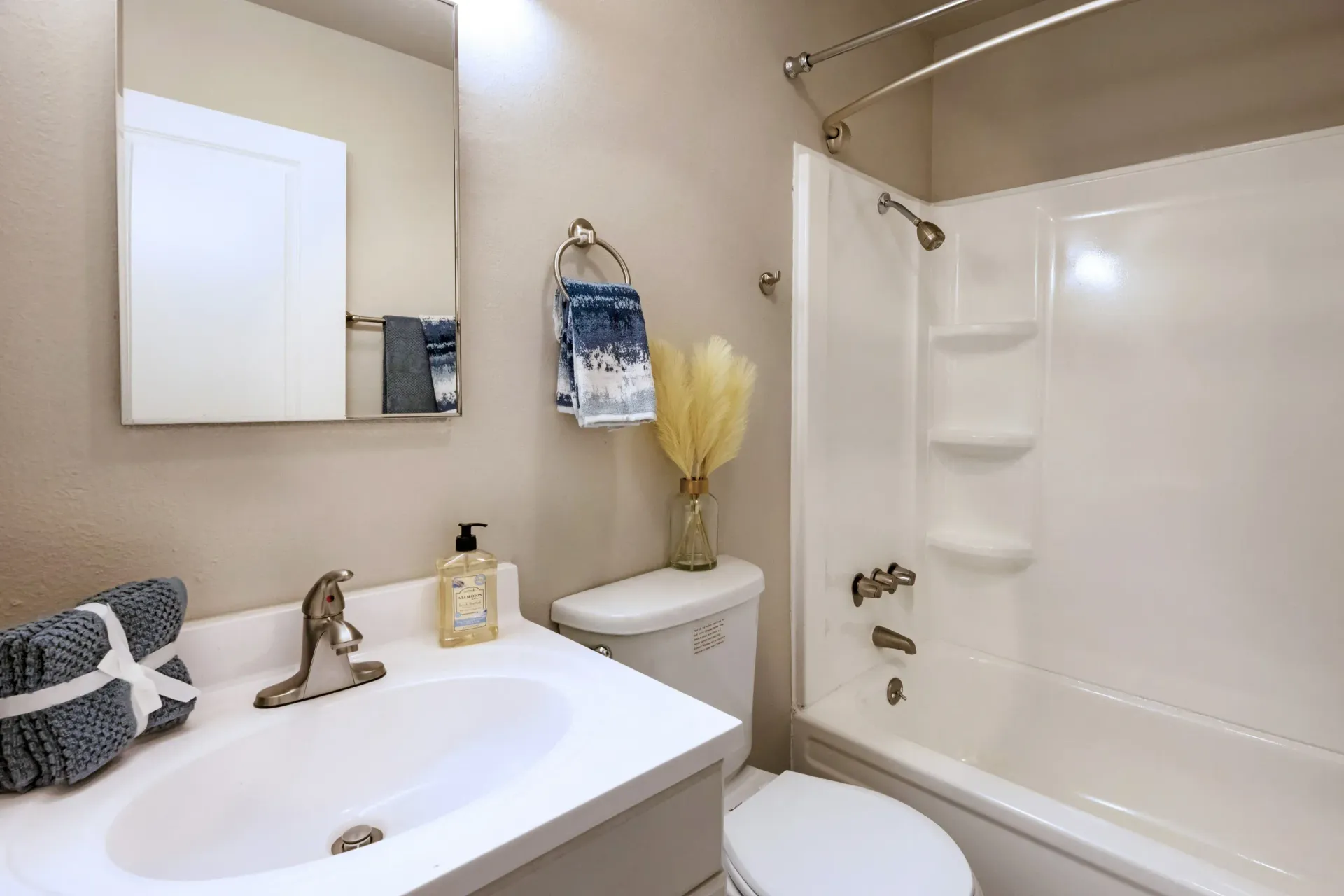 Bathroom with sink, mirror, towels, toilet, and white tub/shower.