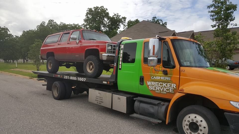 Tow truck hauling a red SUV on a flatbed in a suburban neighborhood