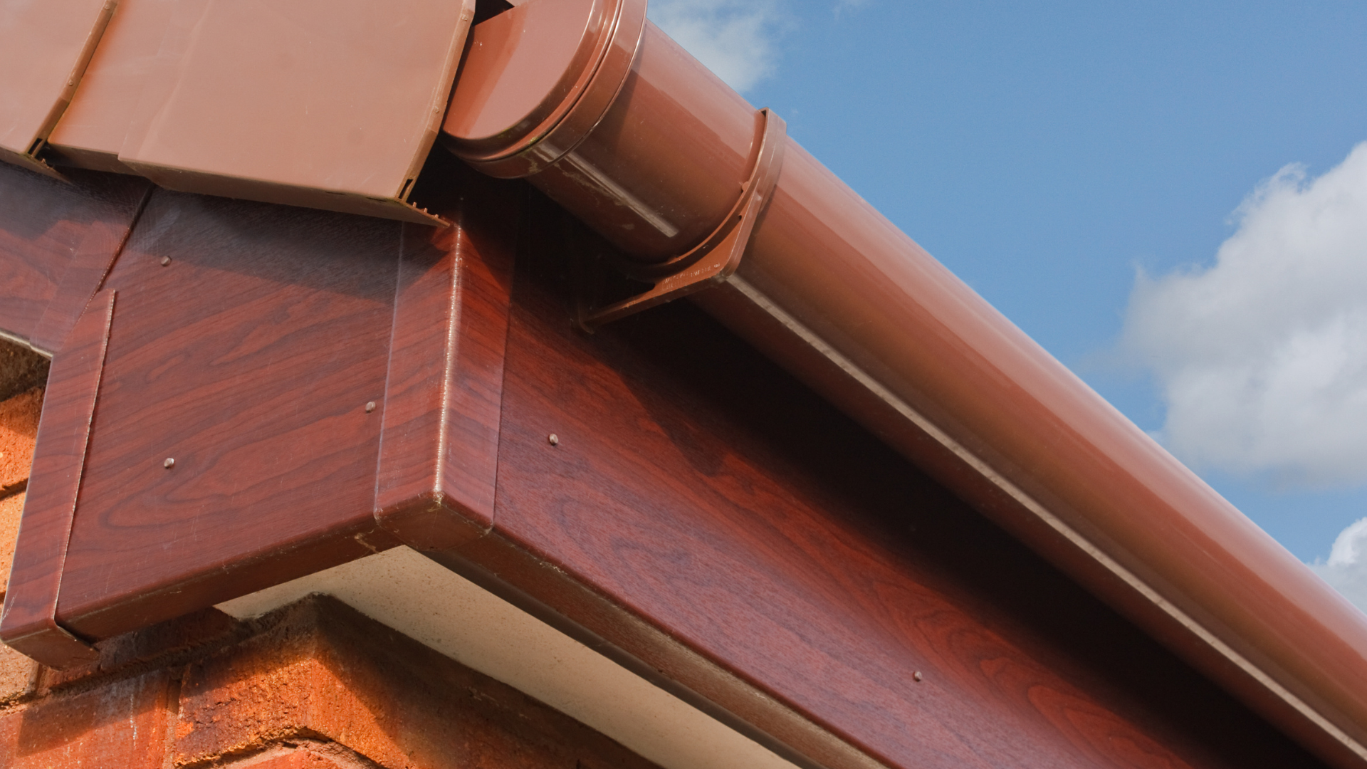 Brown roof with matching gutters and downspout on a house.