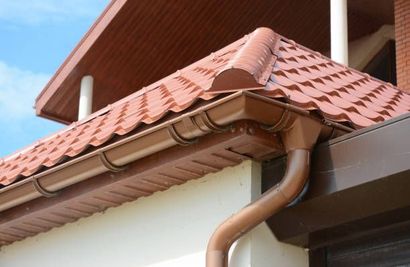 Brown roof with matching gutters and downspout on a house.