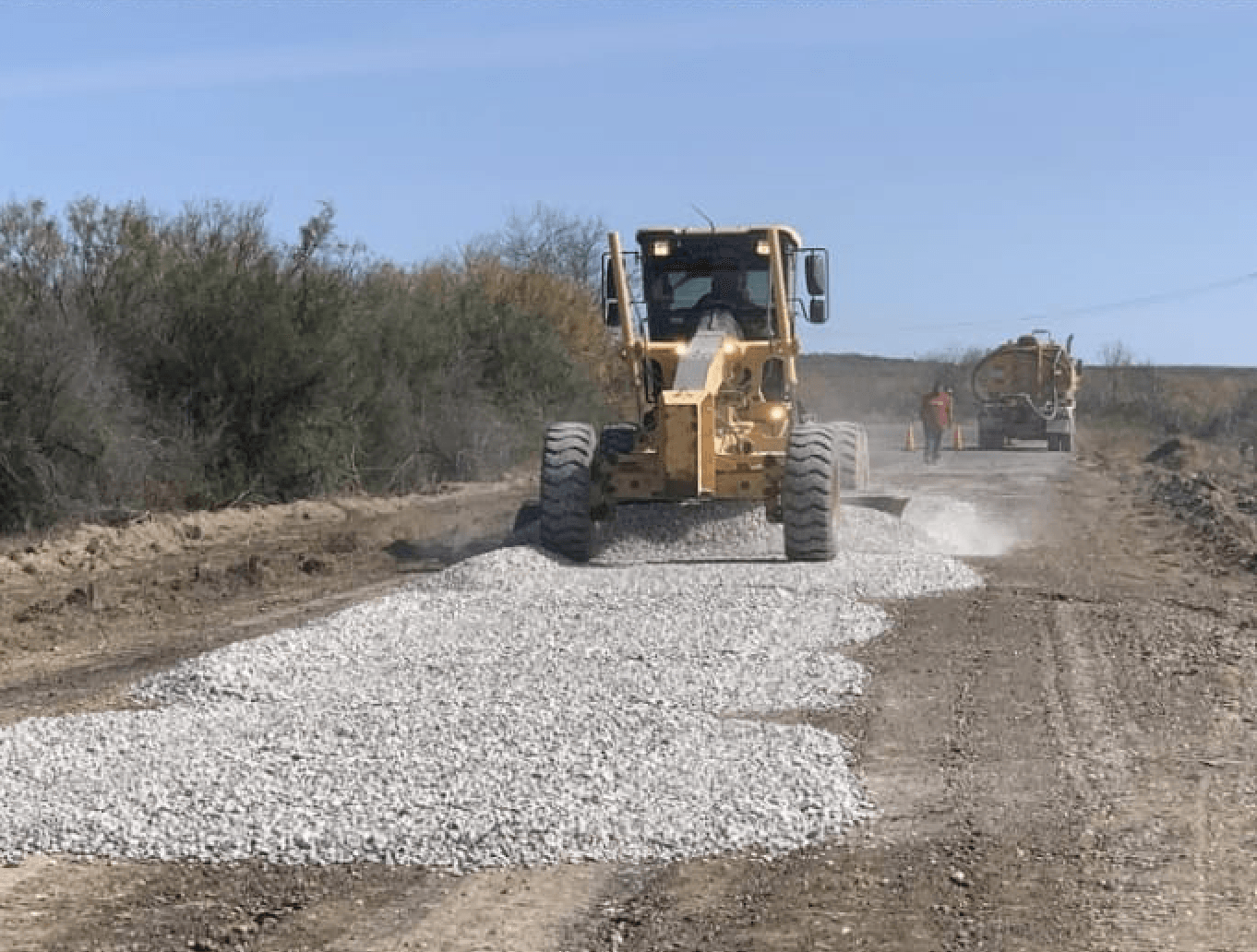A bulldozer is moving gravel on a dirt road