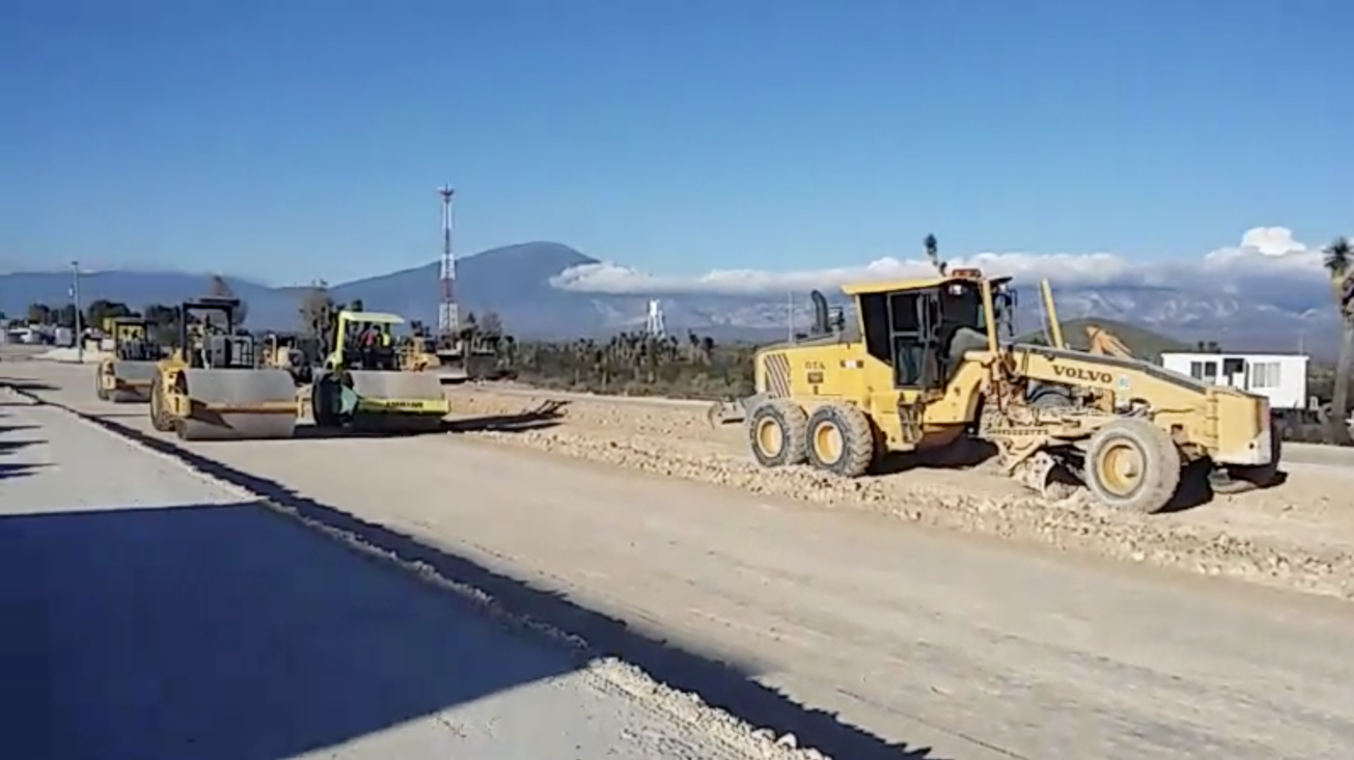 A group of construction vehicles are working on a road.