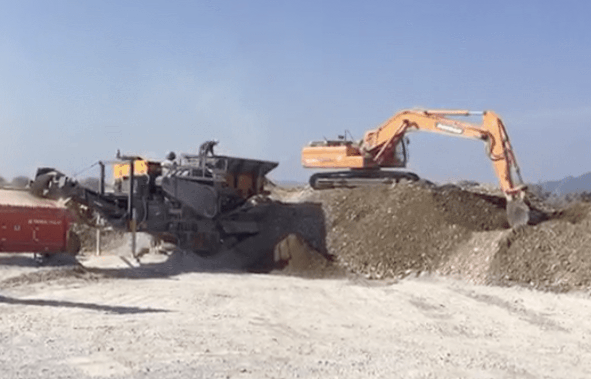 A large excavator is working on a pile of dirt.