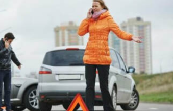 Picture of Lady in orange jacket calling for help with cars in background