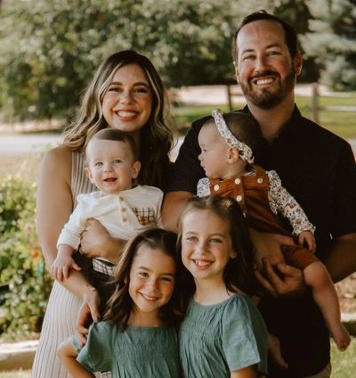 A family is posing for a picture together in a park.