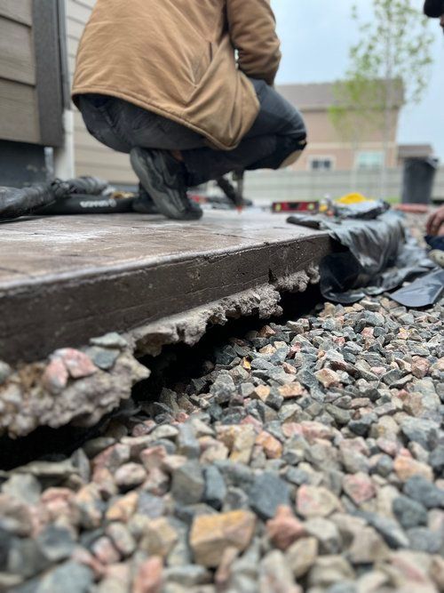 A man is kneeling down next to a pile of rocks.