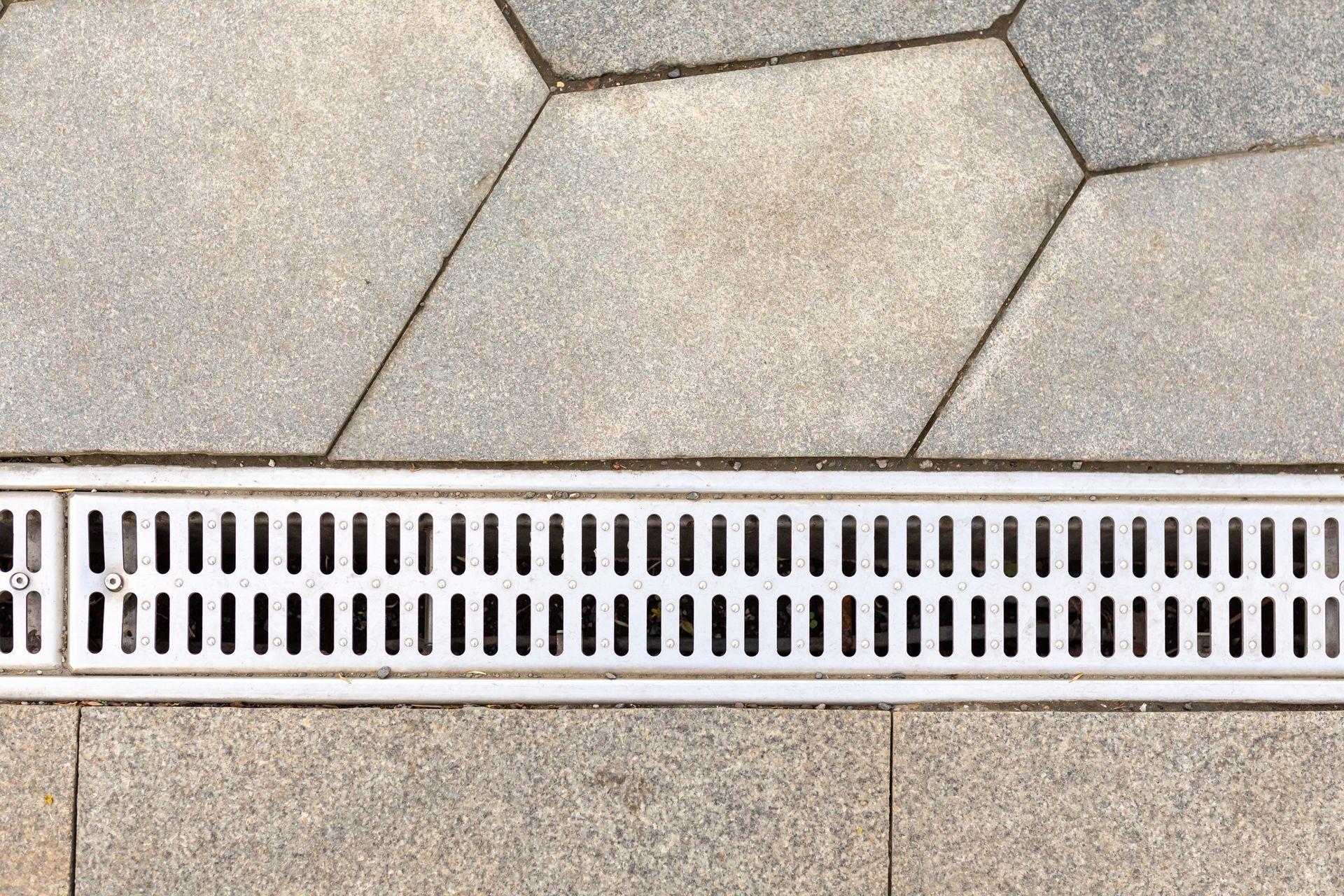 A close up of a drain on a tiled floor.
