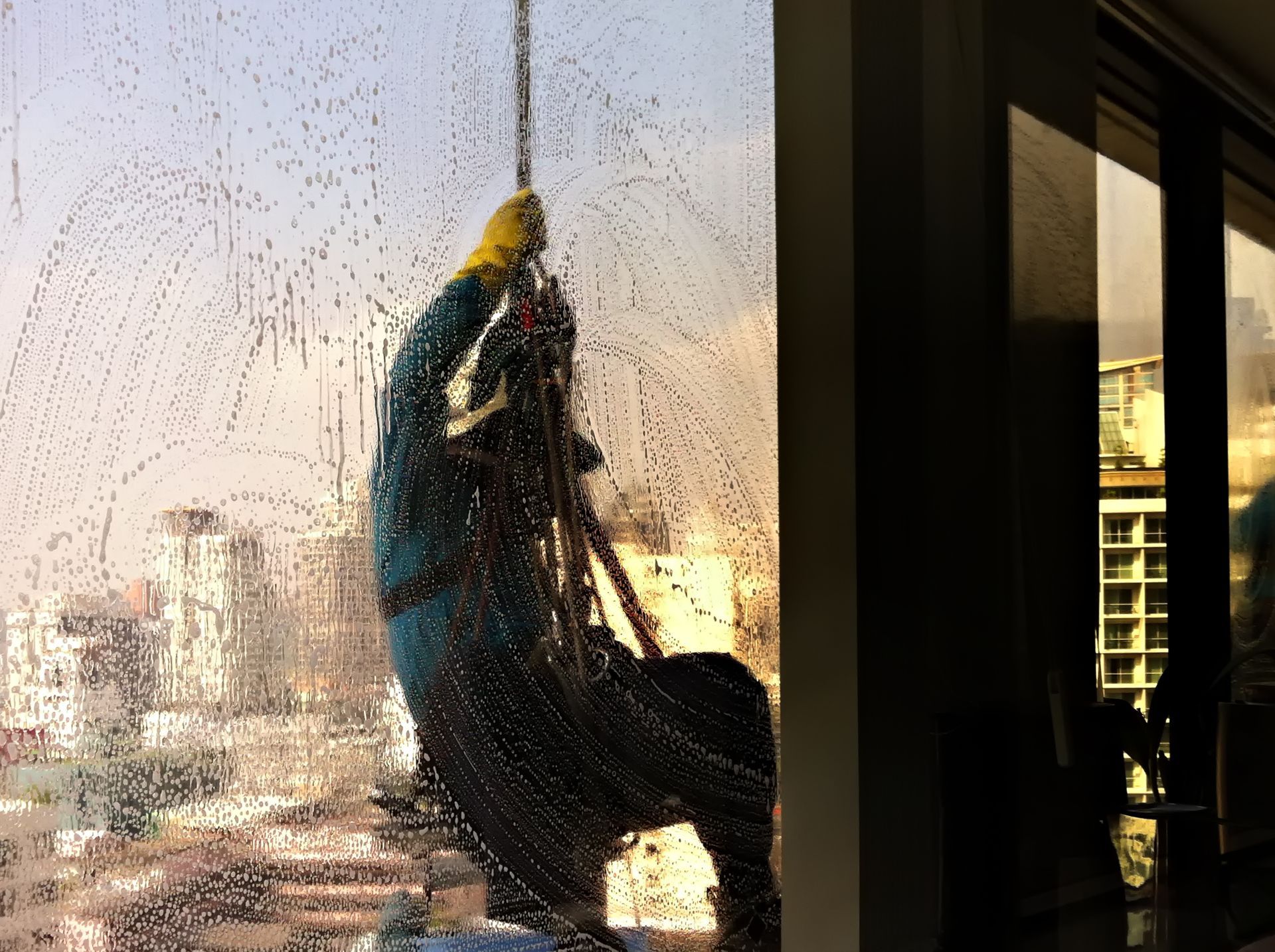 A man is hanging outside a building, cleaning a window.