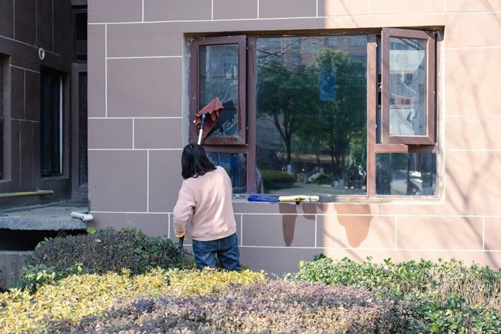 Women cleaning exterior windows of a residential house.