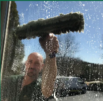 A technician exterior house siding to remove dirt.