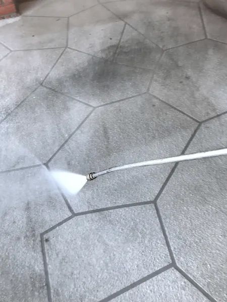 A clean water jet cuts through grime on the surface of hex tiles.