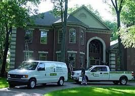 Service van and pickup truck parked in front of a large, traditional brick house. Service van and pickup truck parked in front of a large, traditional brick house.