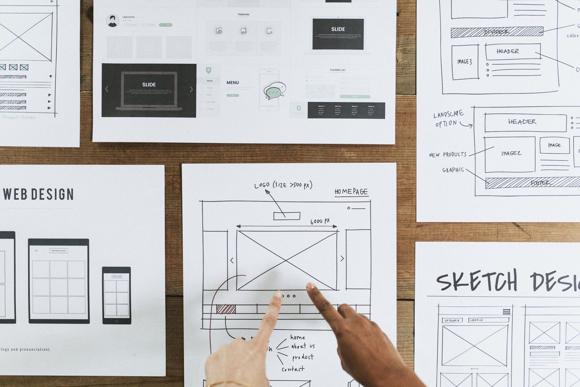 a hand points to sketches on a web design document