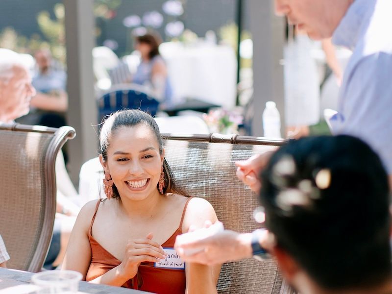Magician David Martinez performs at an outdoor event for a smiling person.