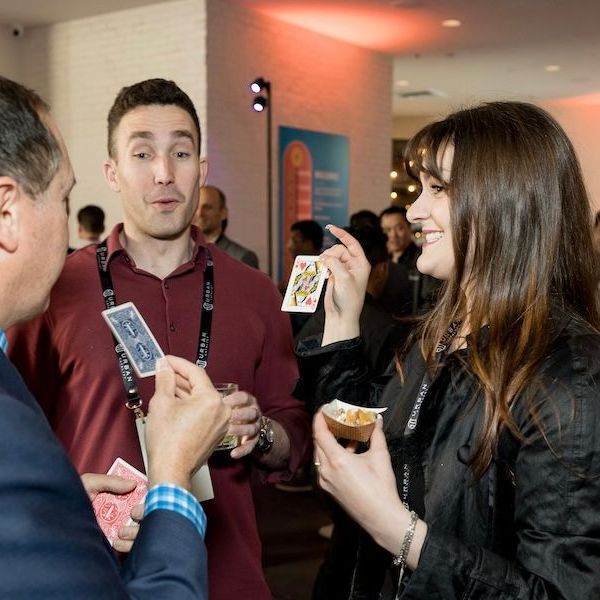 San Francisco Bay Area corporate magician David Martinez demonstrates a fun magic trick to two guests at a company party