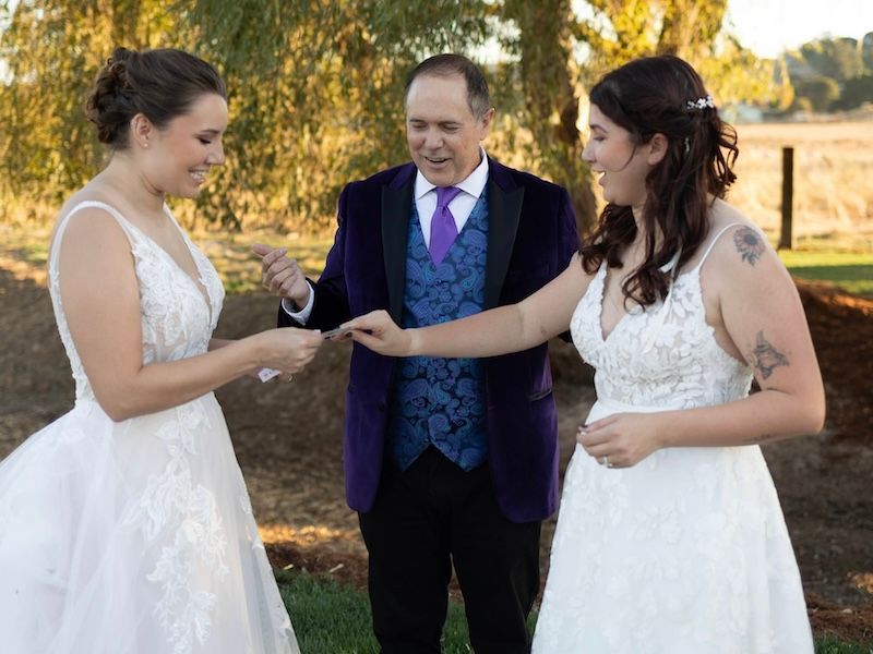 Two brides enjoy a magic trick performed by wedding magician David Martinez
