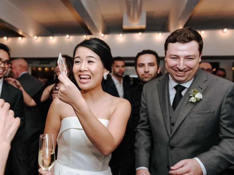 A bride and groom react with smiles at a magic trick performed by wedding magician David Martinez
