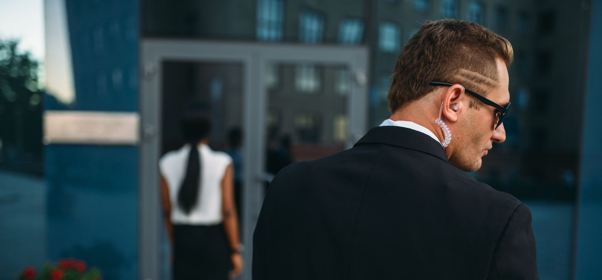 Personal security guard wearing earpiece monitoring surroundings outside.
