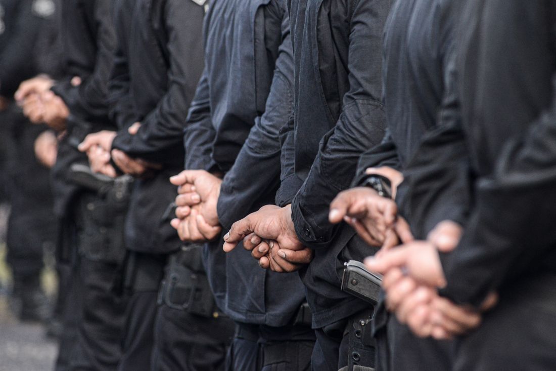 People standing in a line with hands clasped behind their backs.