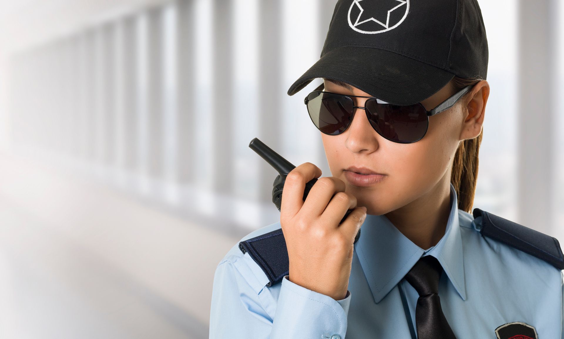 Female unarmed security officer using walkie-talkie in public area, demonstrating professionalism.