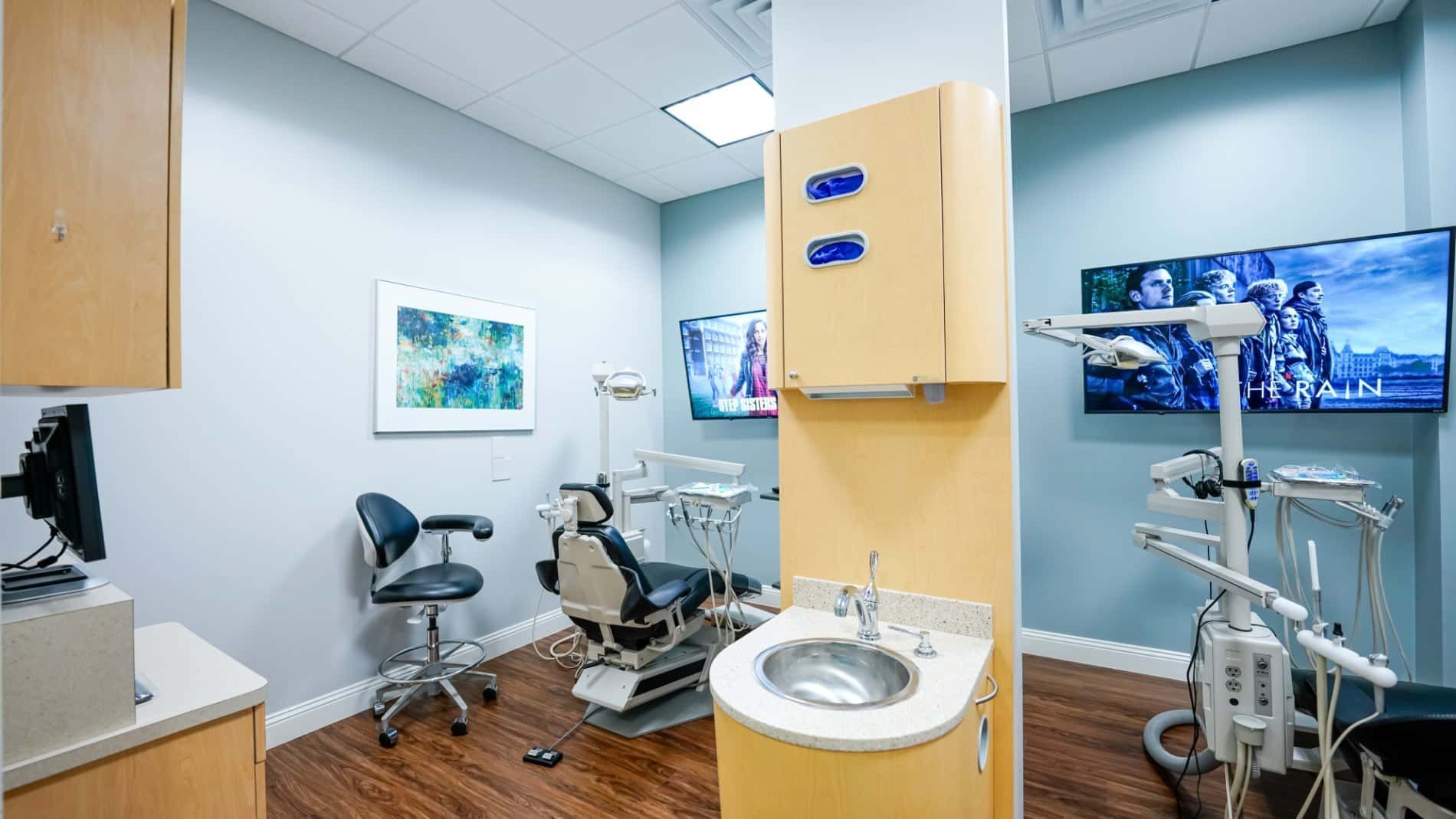 A dental office with a dental chair and sink.